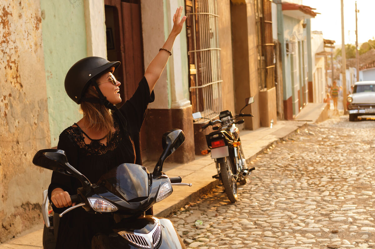 车辆在老城区街道上开着摩托车的女旅行者户外可爱休闲