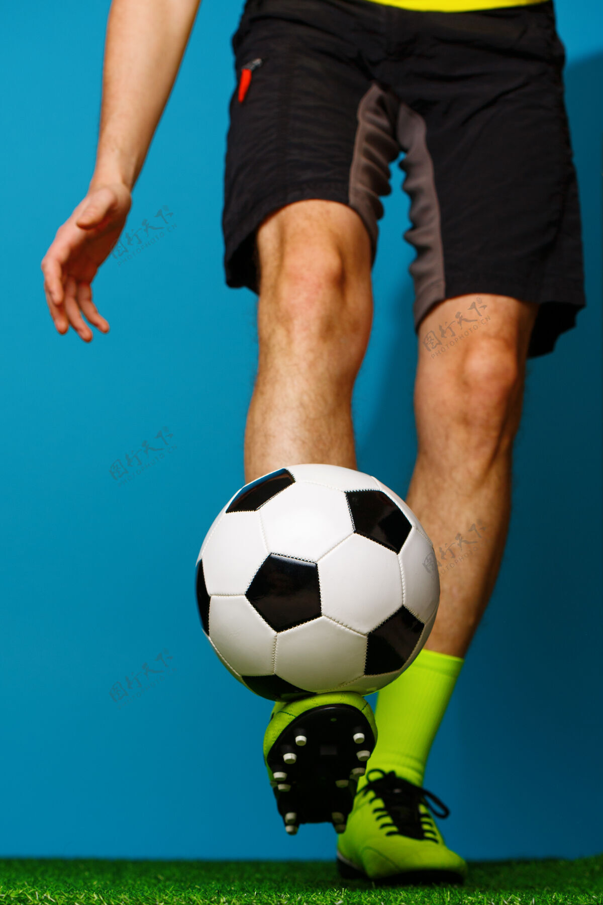 脚在绿草和蓝色背景上拿球的足球运动员欢呼足球比赛