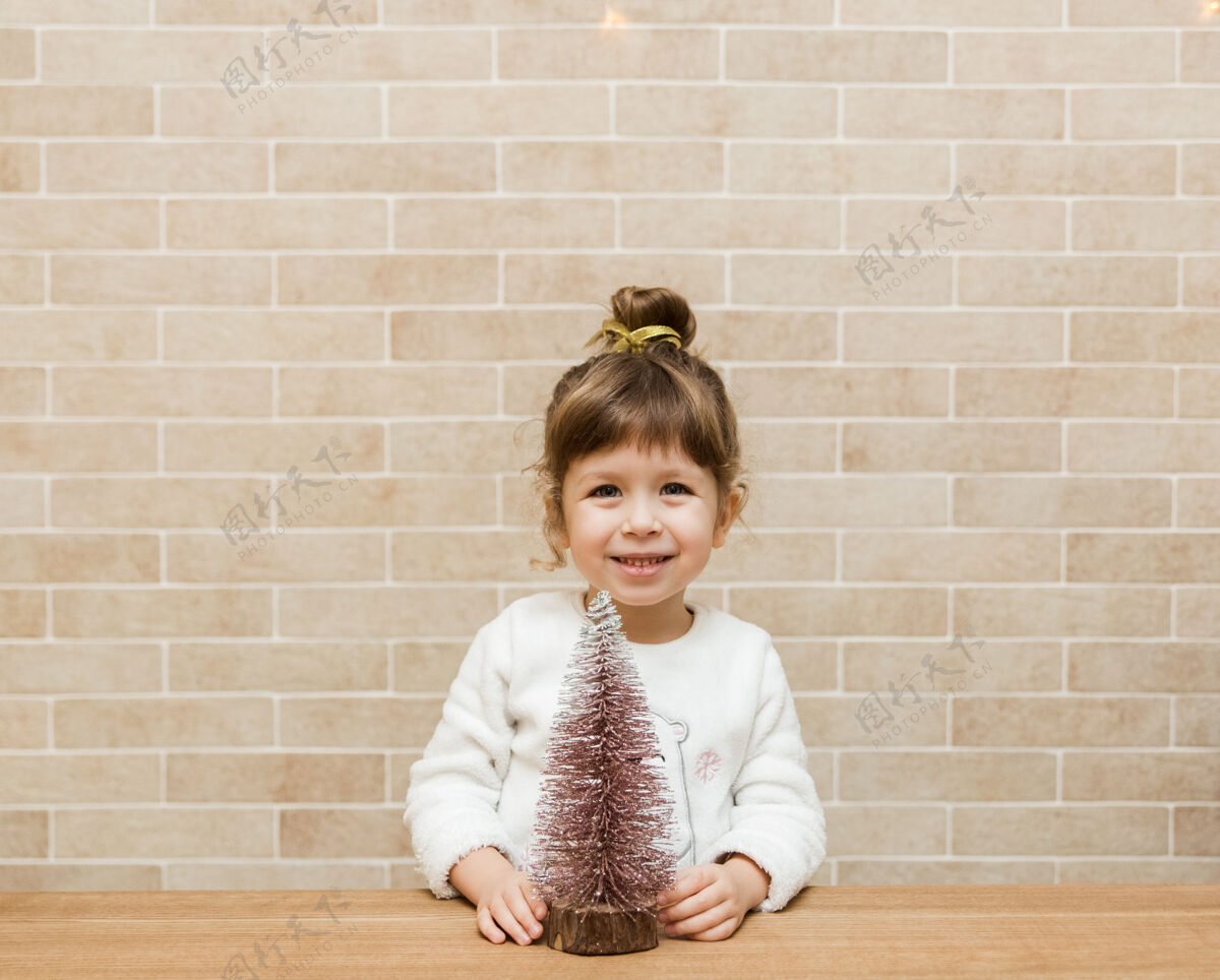 乐趣可爱的小女孩和圣诞节树.砖墙极简主义者时尚愿望节日斯堪的纳维亚