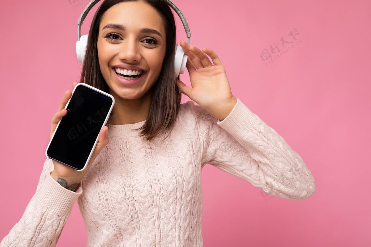 显示器特写肖像美丽可爱的年轻女子穿著粉红色毛衣隔离在粉红色电子手机互联网