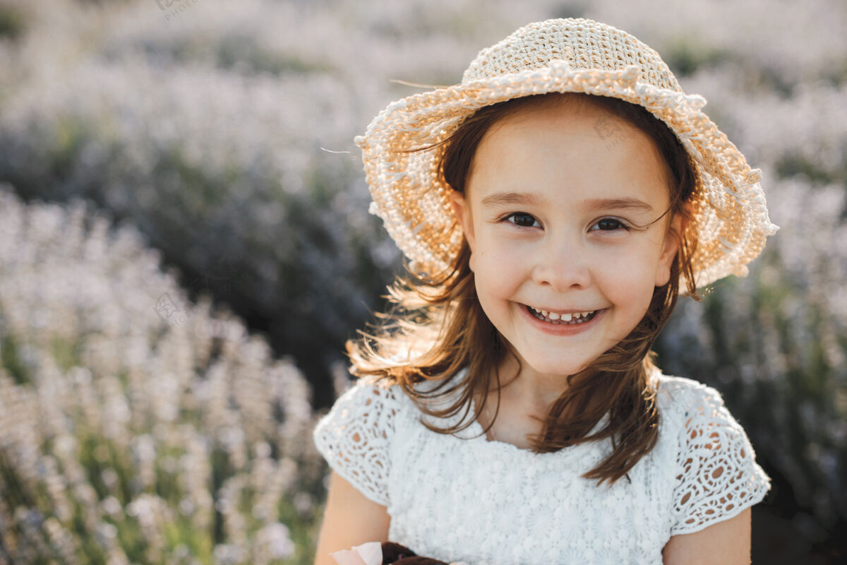 季节可爱的小女孩戴着帽子 穿着白衬衫 对着一片鲜花笑着风景田野孩子