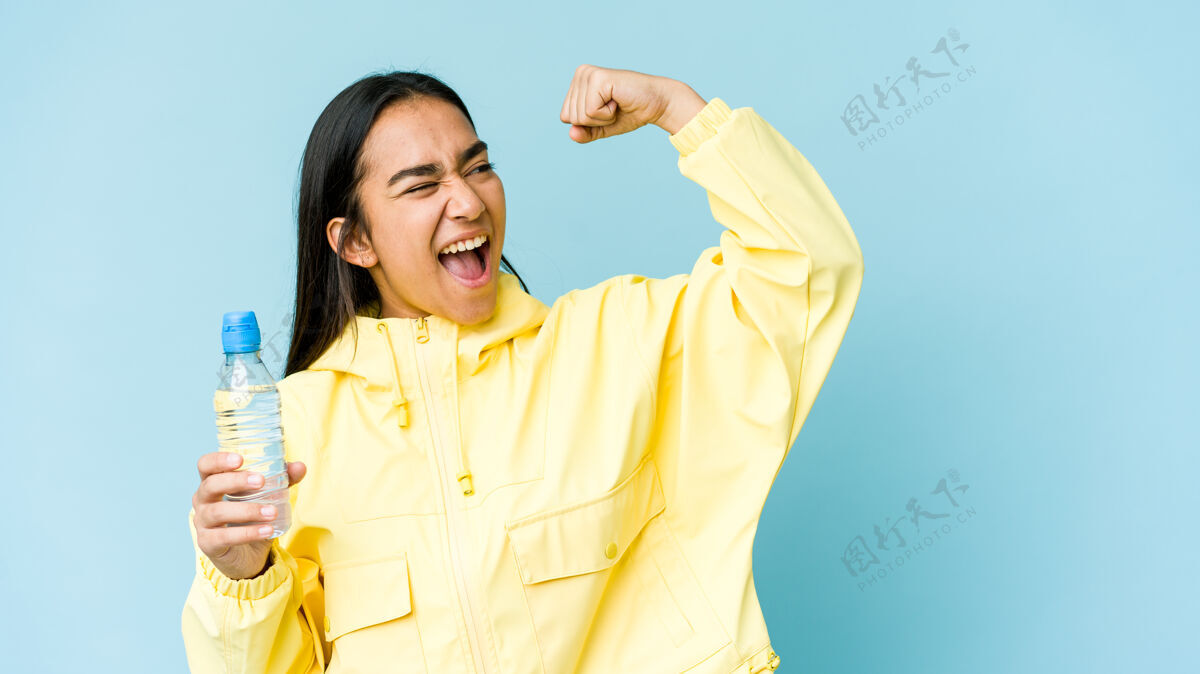肖像年轻的亚洲女子手持一瓶水举起拳头 胜利后 赢家的概念跳跃兴奋呼吁