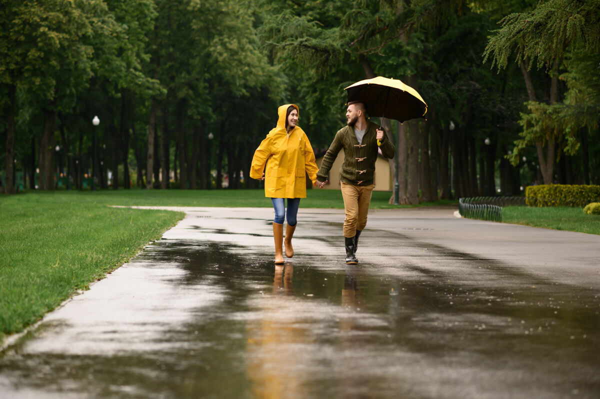 家庭快乐的情侣在公园里奔跑 夏日多雨戴曼雨伞下的女人 散步路上的浪漫约会 小巷里的潮湿天气女朋友丈夫女人