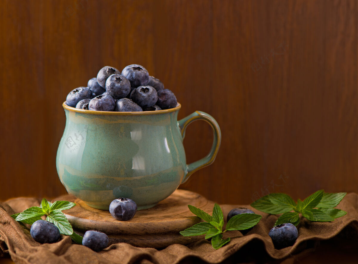 越橘一杯新鲜的蓝莓和薄荷叶浆果背景碗