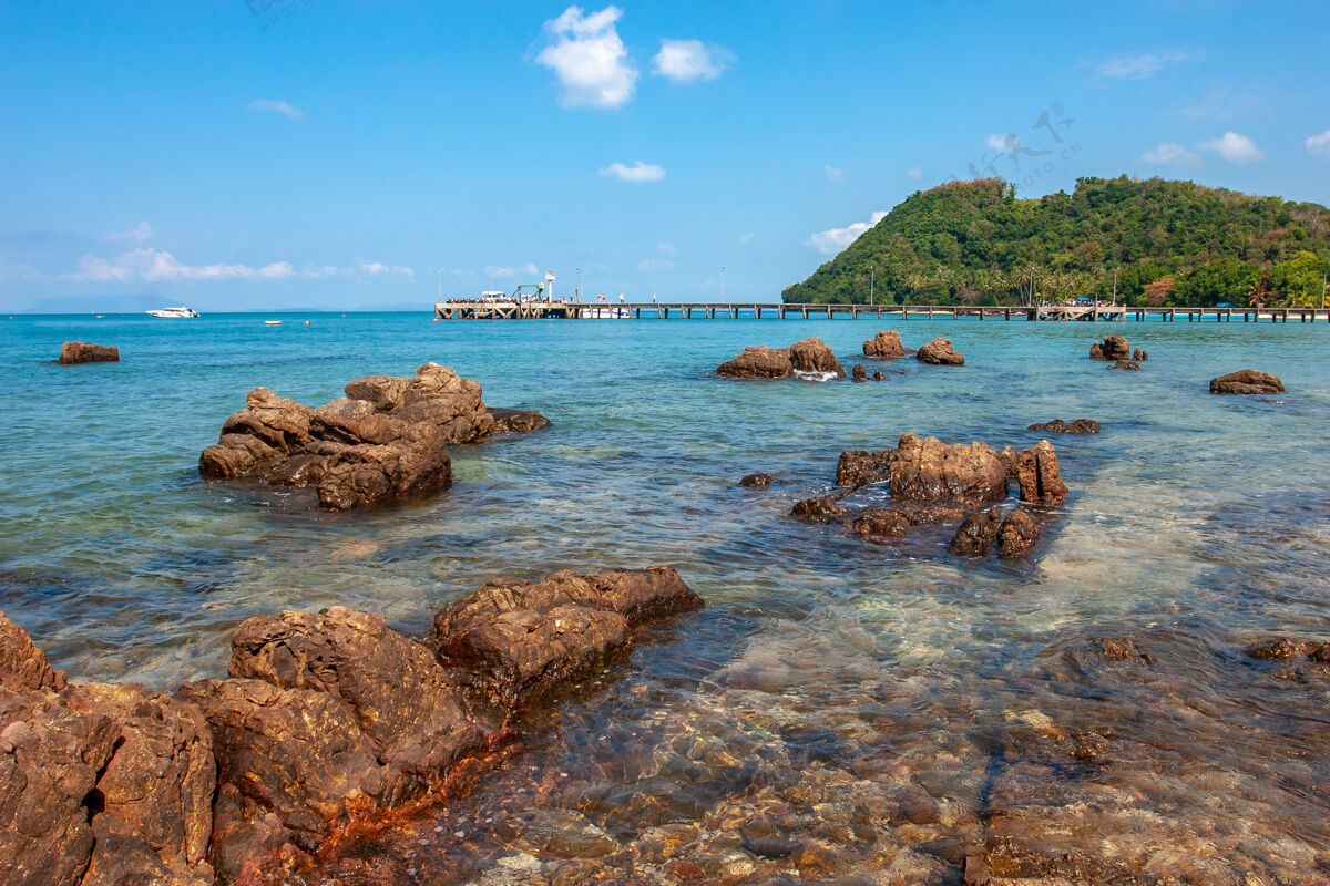 放松美丽的石头在绿松石海和码头热带海浪海岸