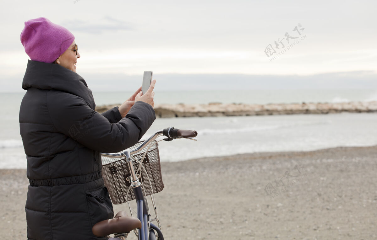 快乐优雅的女人 骑着自行车 用着自行车手机近大海 文字的空间男性海滩休闲