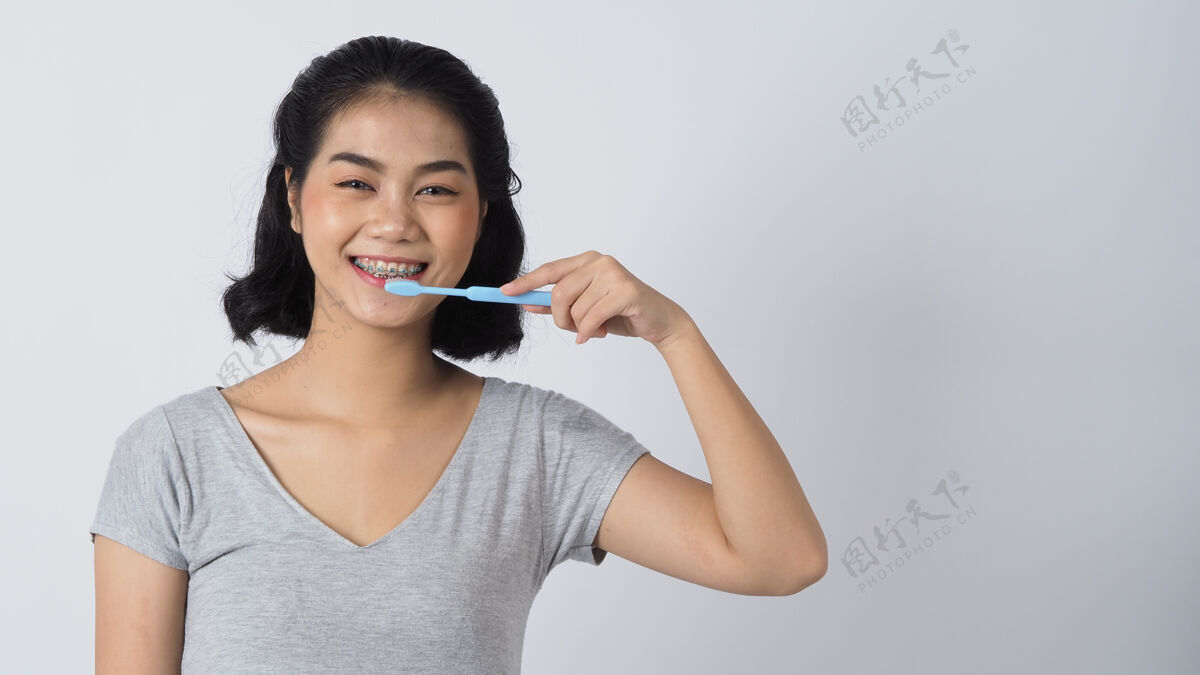 正畸牙托少女微笑着拿着牙刷白牙配蓝牙牙套亚洲护理戴隐形眼镜和正畸的妇女配件.化妆品牙科手势看牙医