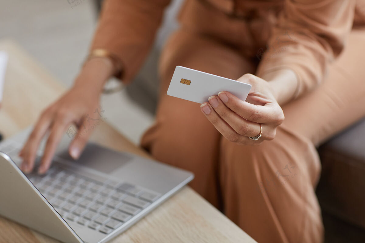 无法辨认的人坐在桌边使用笔记本电脑和信用卡在线支付购物的女人的特写镜头成人使用计算机计算机