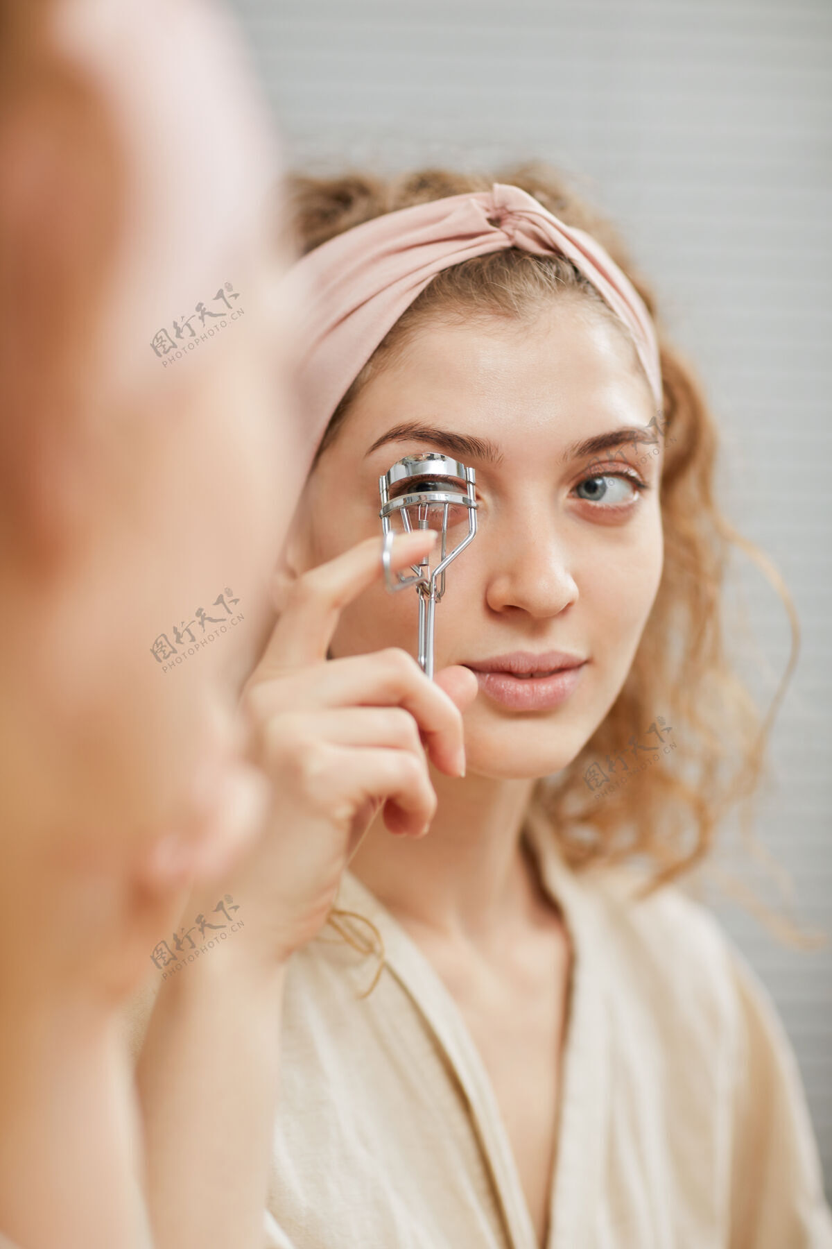 人手年轻漂亮的女人在化妆前照镜子 照顾她的睫毛肖像美女欢呼