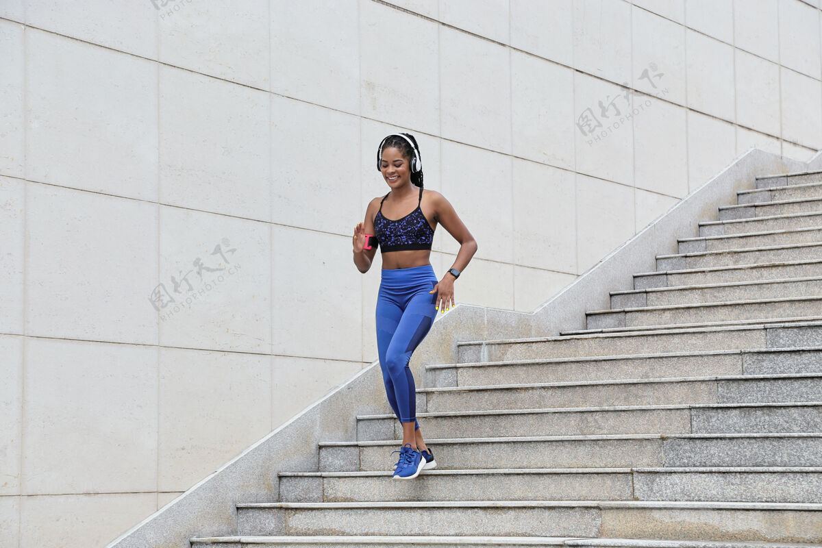 体育活动在马拉松训练中 一位年轻的女运动员微笑着跑下楼梯台阶慢跑楼梯