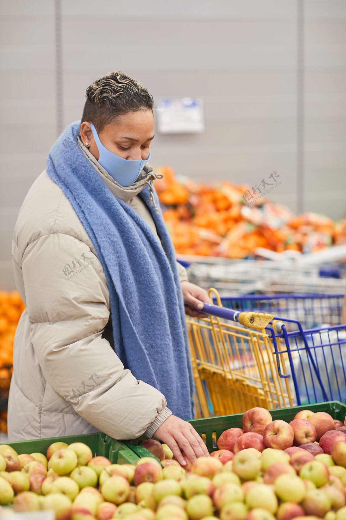水果穿着暖和衣服 戴着面具的年轻女子在超市挑选新鲜水果苹果蔬菜健康饮食