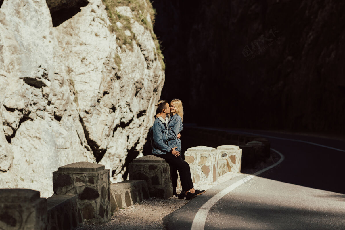 活跃漂亮的夫妇站在路上 墙上有石头和石头亲吻白种人散步