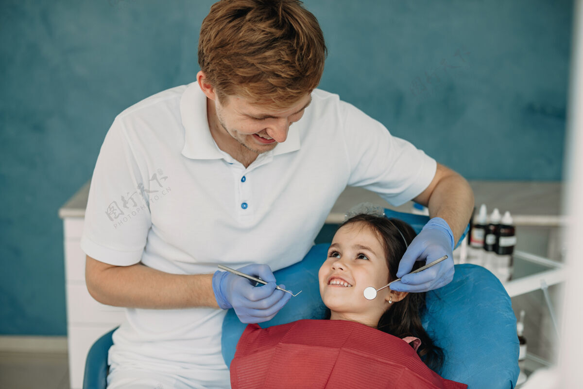 牙医可爱的小女孩看着她的牙医微笑着做牙齿检查口腔设备制服