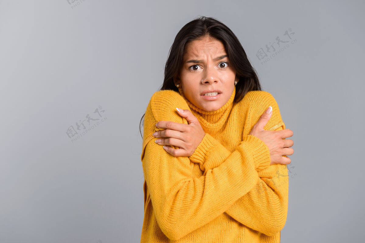 套头衫一个穿着毛衣的冻僵的年轻女子孤零零地站在灰色的墙上 颤抖着女性长相白种人