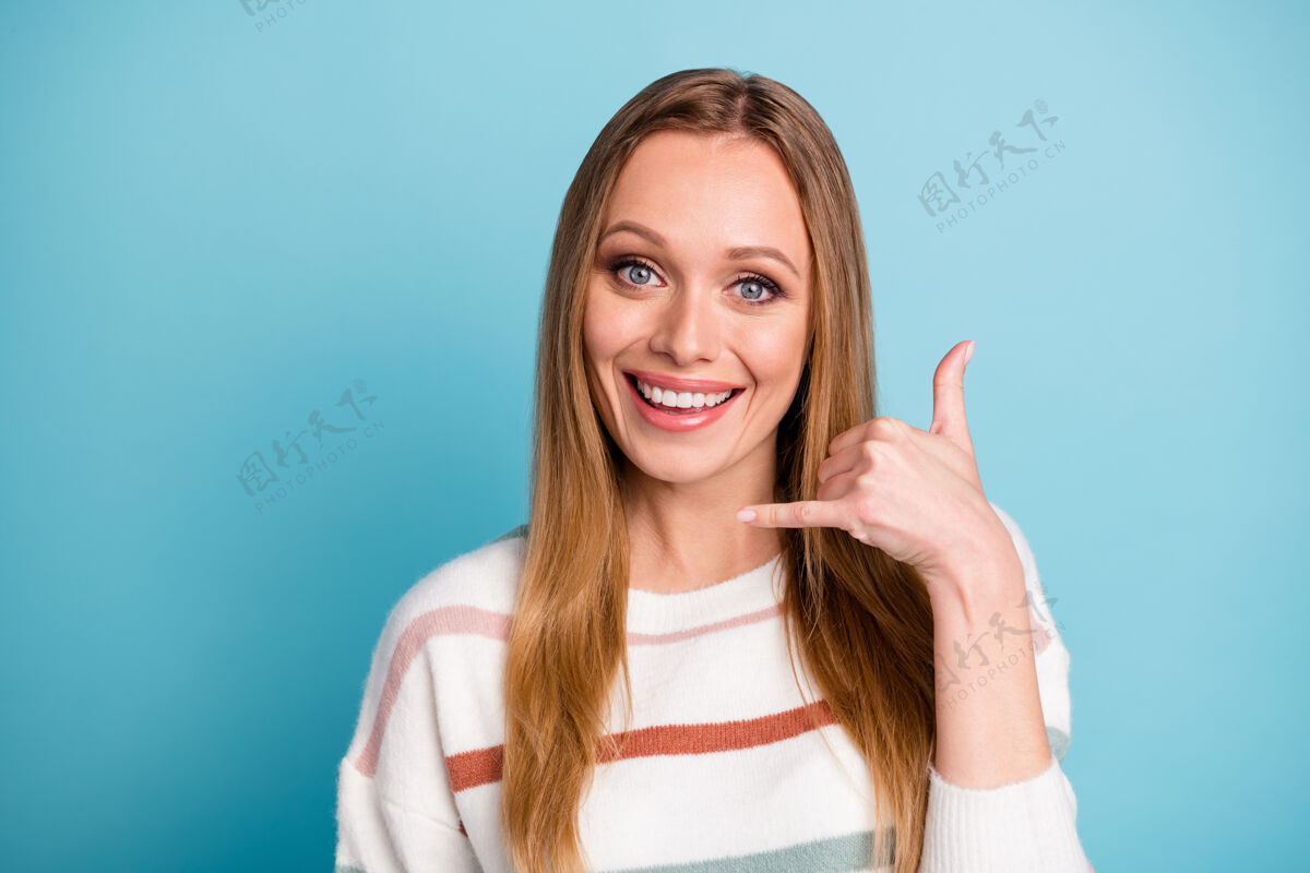 秀开朗积极可爱可爱甜美的女人微笑着牙齿的手指表示有机会打电话给她单独粉彩蓝色墙壁倾听毛衣时尚