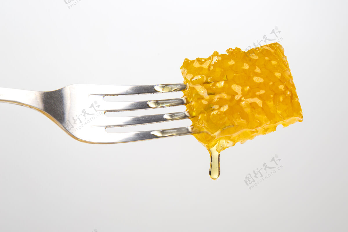 甜点几滴新鲜的蜂蜜从蜡蜜滴到桌子上叉子维生素营养和蜂产品花蜜打蜡配料