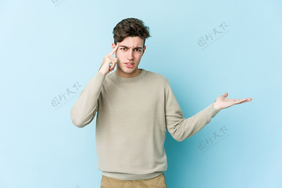 手臂一个年轻的白人男子拿着一件产品 在蓝色的空间里与世隔绝手掌演示指向