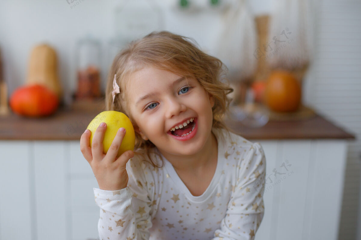 金发女孩厨房里的小女孩在家吃苹果健康健康女孩
