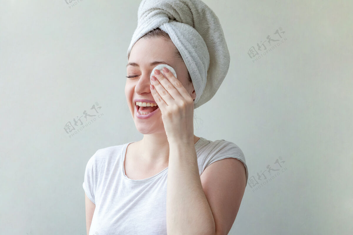 纯净头上戴着毛巾的微笑女人的美丽肖像 柔软健康的皮肤 用隔离在白色背景上的化妆棉卸妆洗触摸卫生