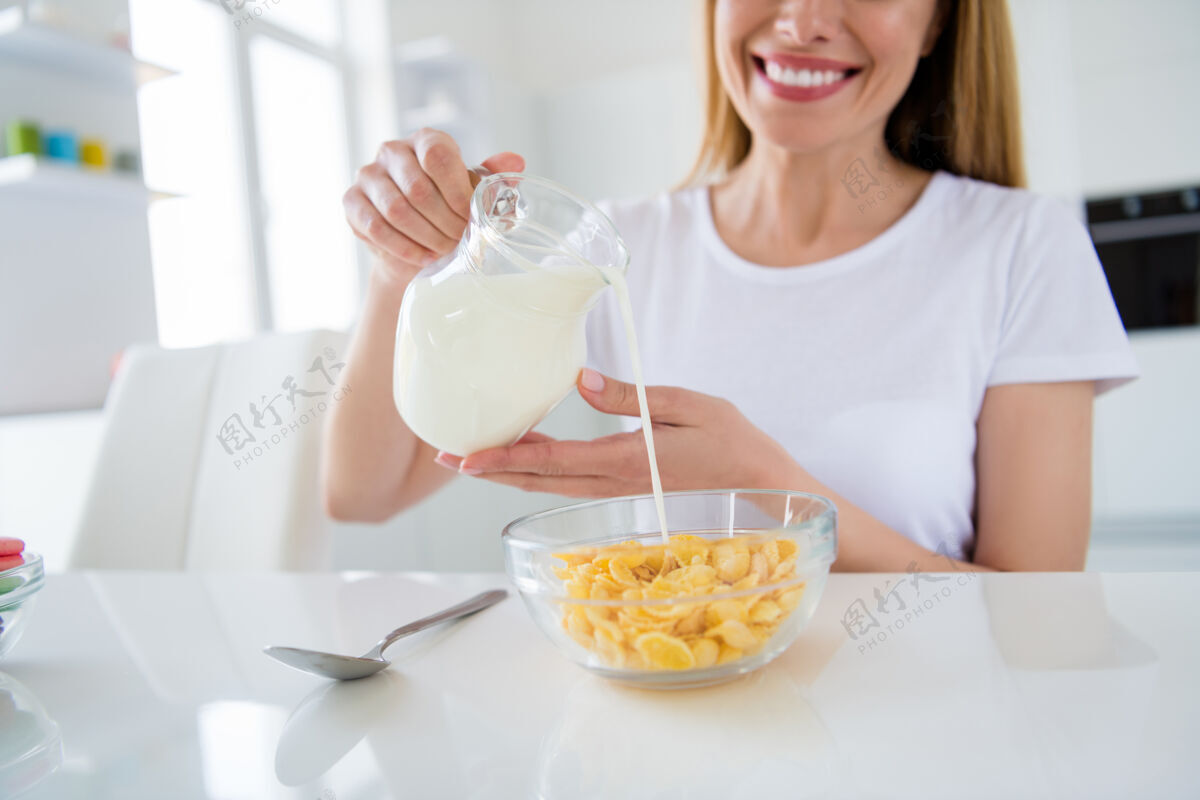 庄稼家庭主妇手拿倒鲜奶煮早餐玉米片美味健康饮食概念室内白光厨房的不规则照片小吃烹饪格兰诺拉麦片