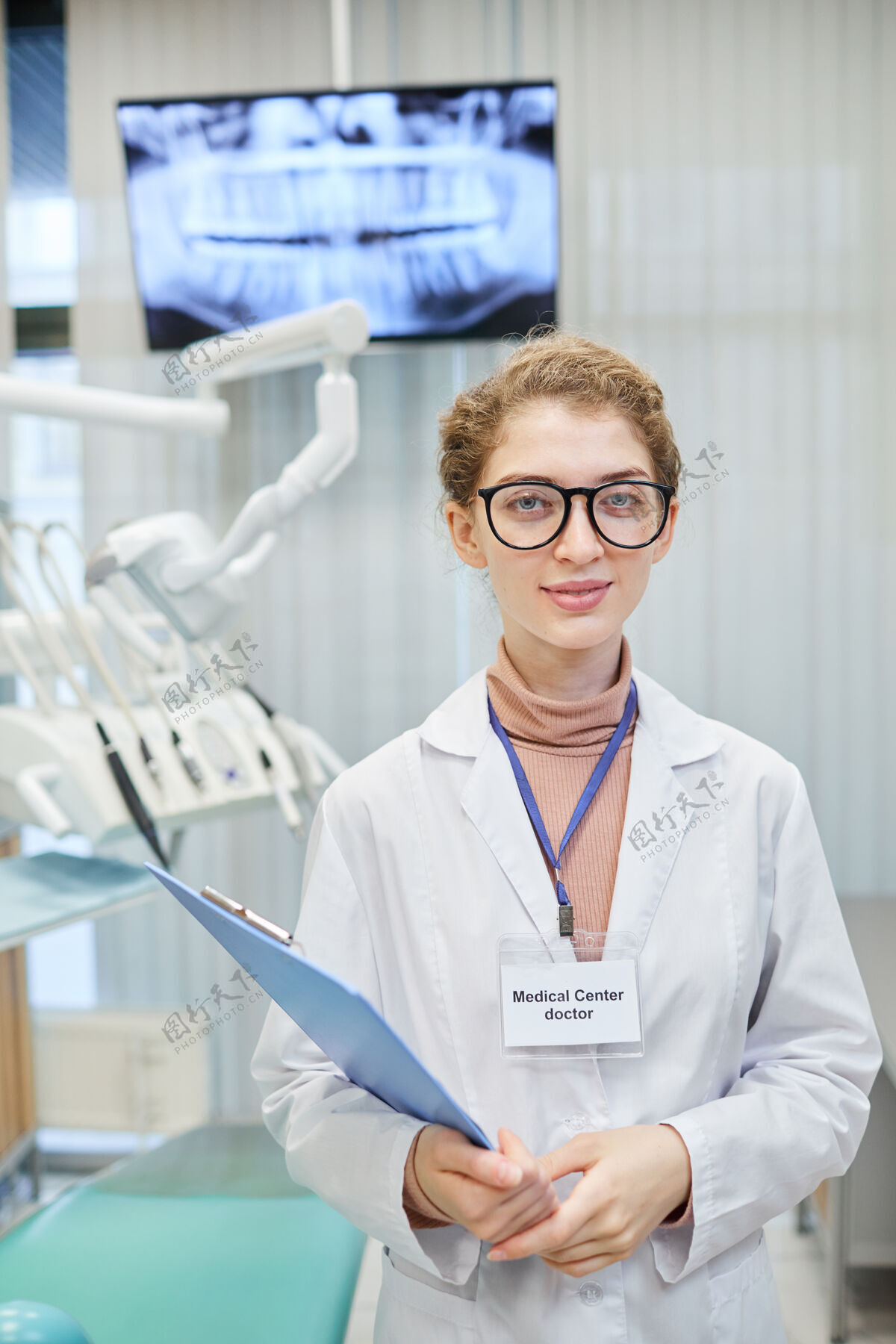 表情在牙科诊所工作时 身穿白大褂的女医生手持医疗卡望着前方的画像快乐护理正面视图