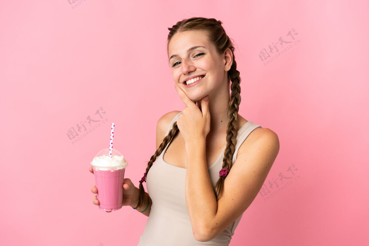交叉年轻的女人用草莓奶昔隔离在粉红色的快乐和微笑有机大笑女人