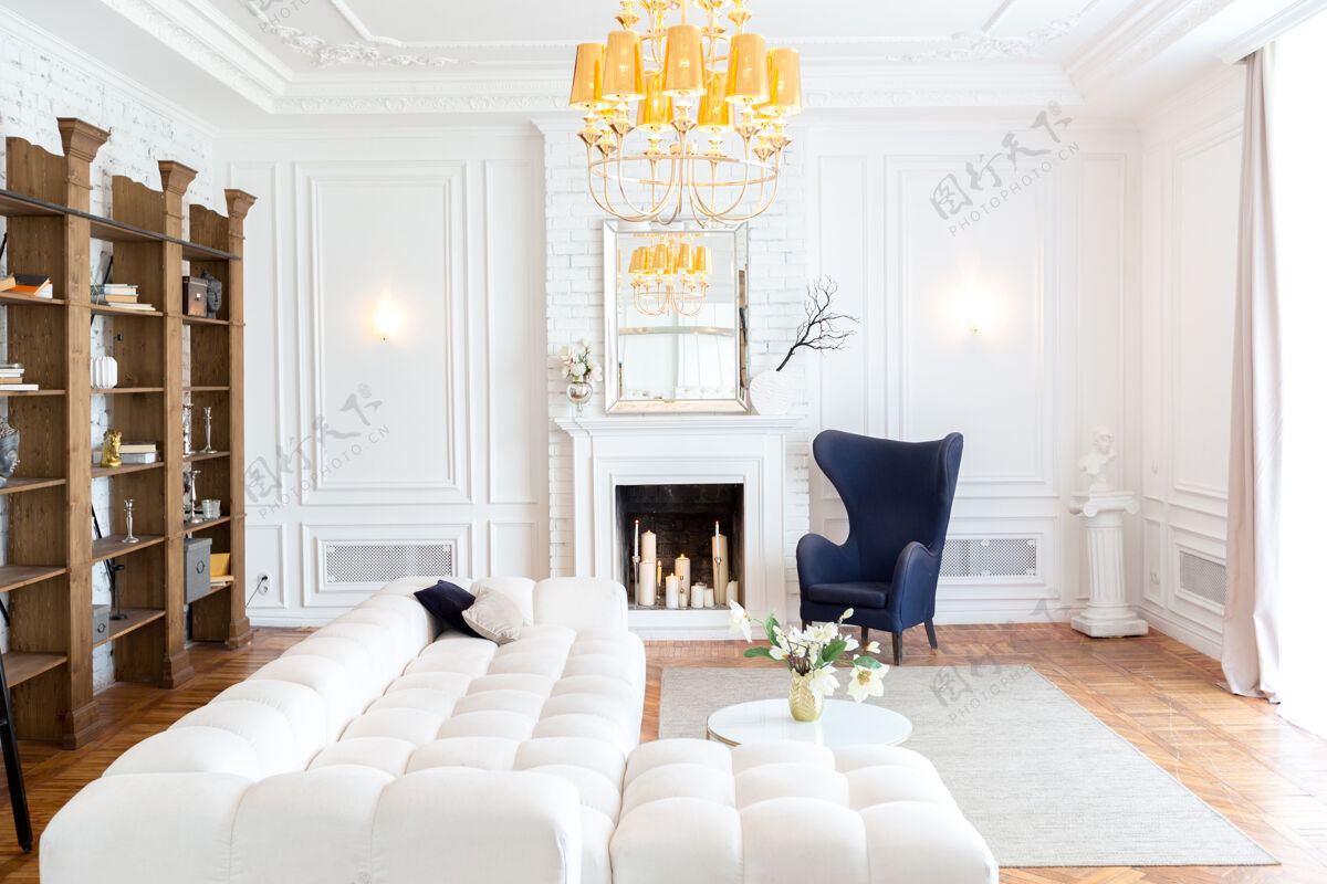 室内豪华宽敞明亮的现代室内房间白色昂贵的沙发和木制架子 白色的墙壁和一个豪华的枝形吊灯公寓家庭内部时尚