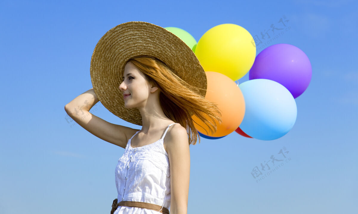 衣服红发女孩带着彩色气球在蓝天上红色户外游戏