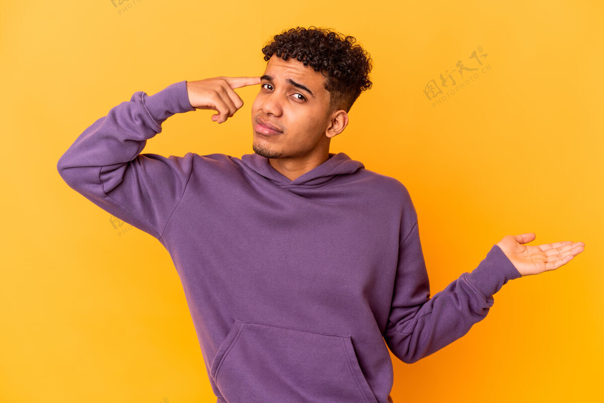黑色年轻的非洲裔美国卷发男子拿着黄色的手 并显示一个产品在手持有英俊卷发