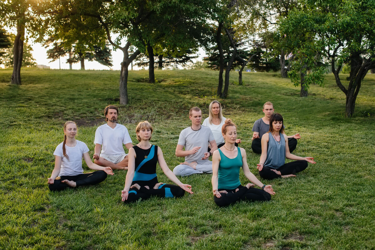 微笑一群人在日落时分在公园里做瑜伽健康的生活方式 冥想和健康放松日落活动