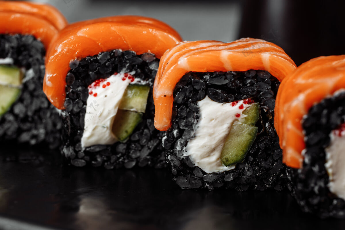 筷子一套寿司卷费城与红鱼 奶油奶酪和黑色上升躺在一个盘子船鲑鱼酱油日本