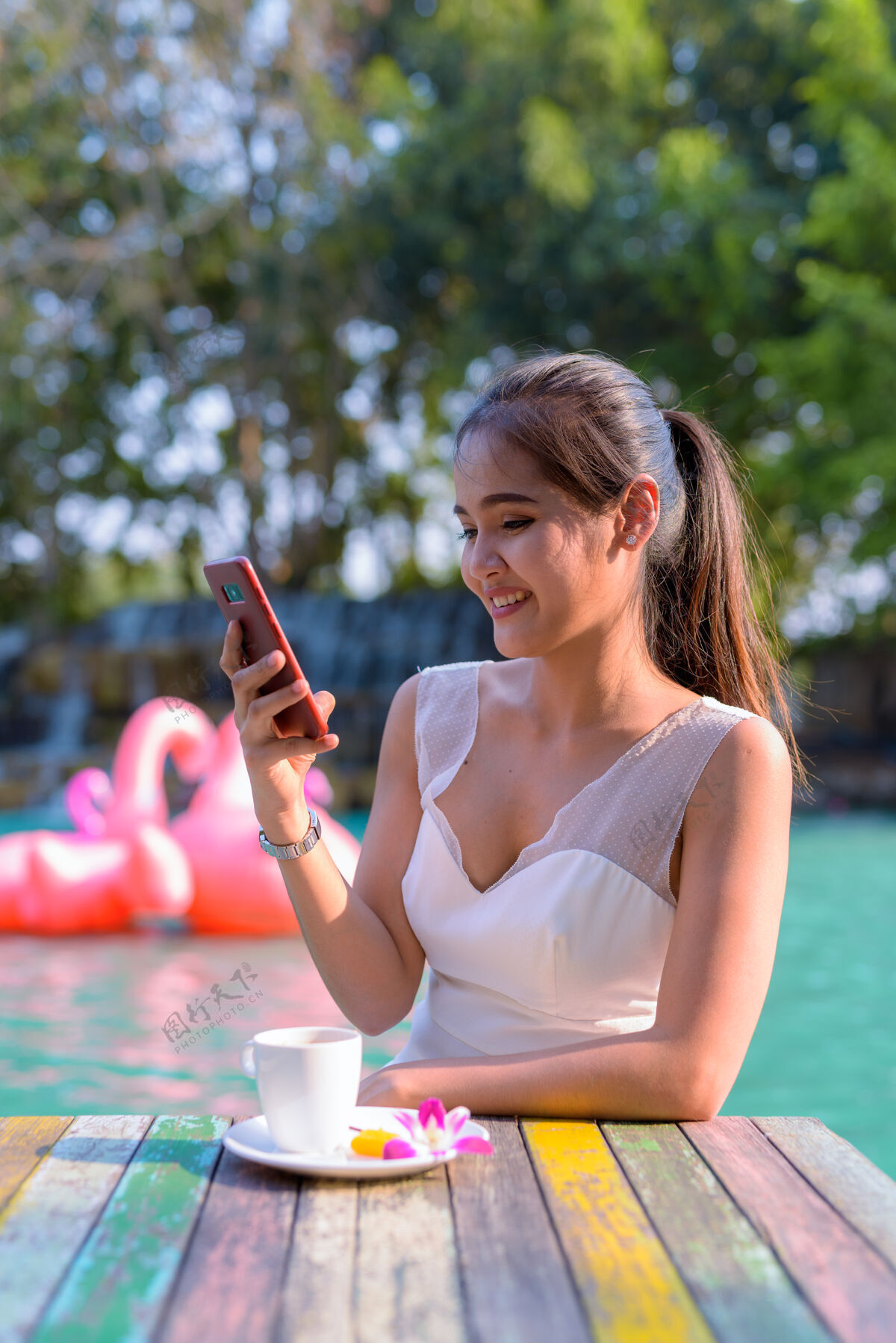 游客年轻美丽的亚洲女游客在湖边户外放松的画像手机快乐泰国
