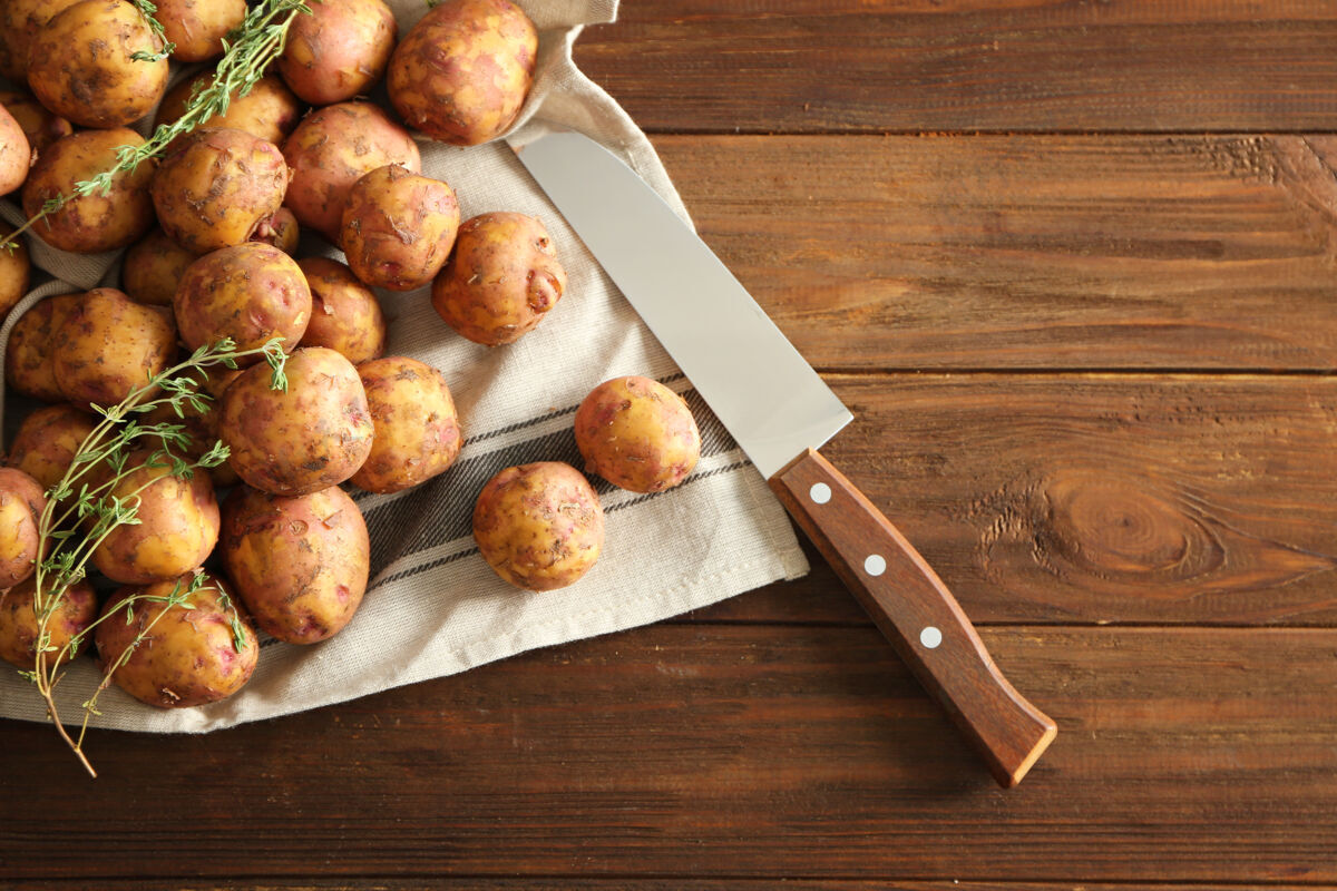 土豆在木桌上用刀切生的有机土豆生的乡村营养