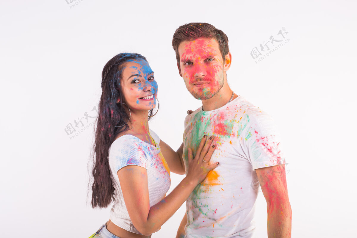 明亮友谊 爱情 胡里节 人的概念-年轻夫妇在白色的胡里节上玩色彩家伙文化多彩
