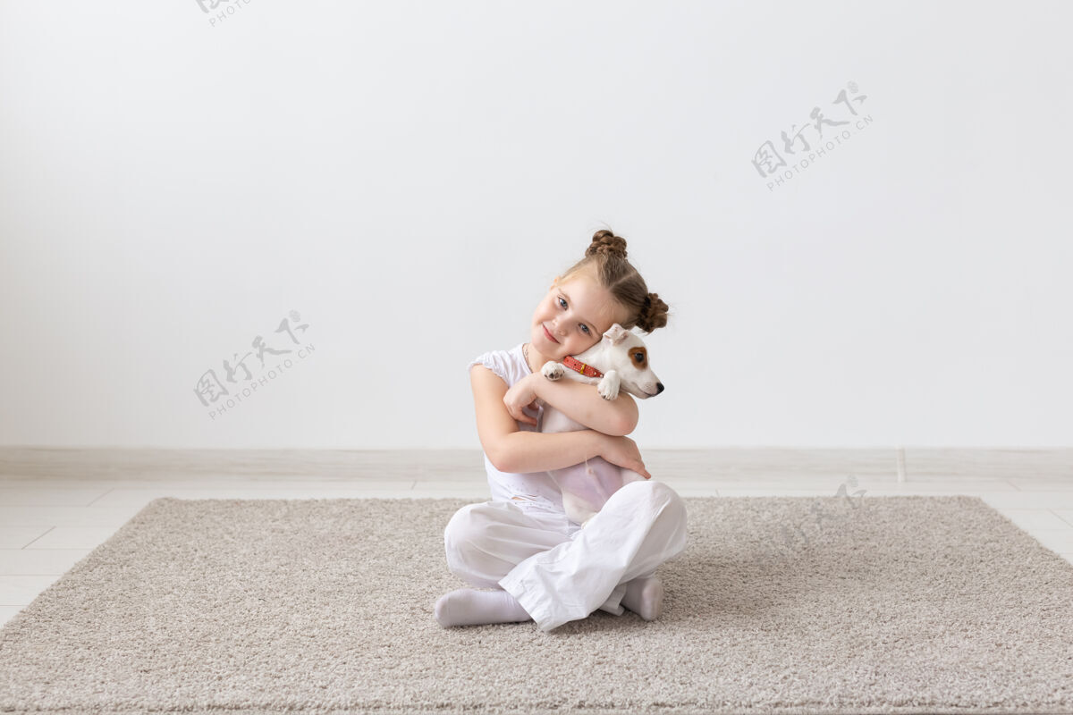 人类宠物 童年和动物的概念-画像的小女孩坐在地板上与小狗杰克罗素梗玩友谊国内