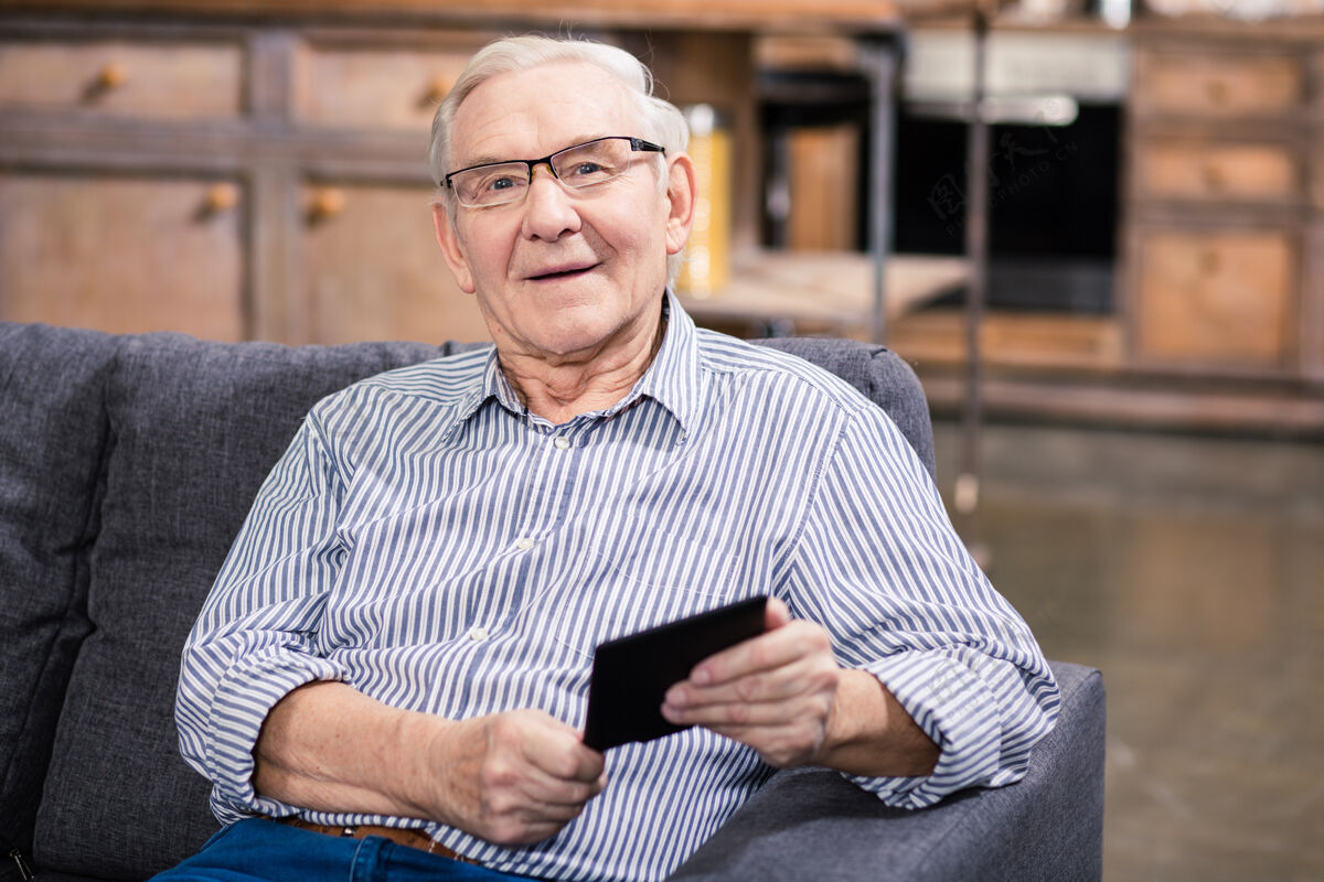 社交一个快乐的老人一边休息一边拿着一本电子书成人技术老年