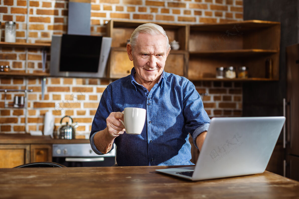 家庭积极的老人微笑着使用笔记本电脑和在厨房喝茶微笑休闲休息