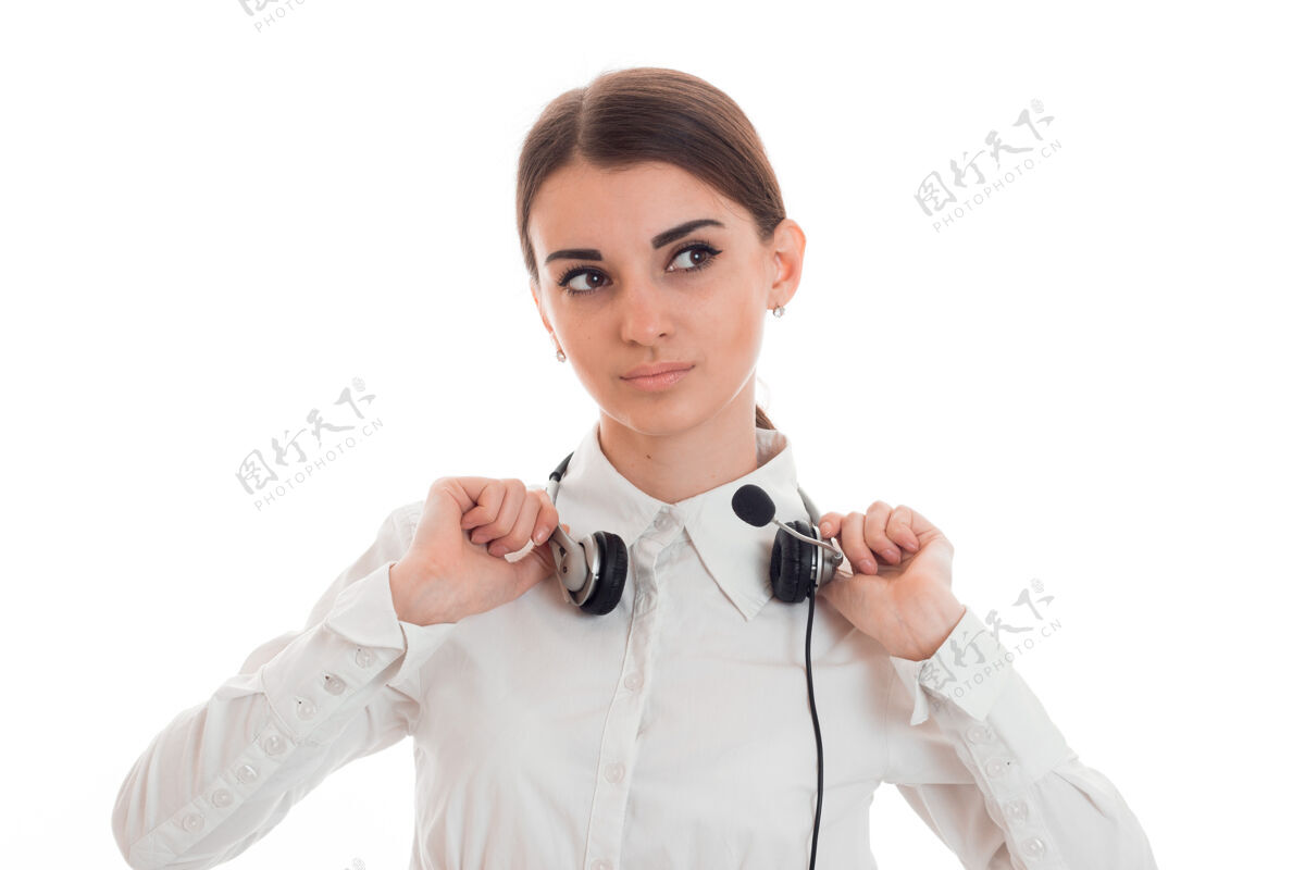 信心年轻的呼叫中心接线员穿着白衬衫 耳机被隔离在录音室的墙上可爱女士模特