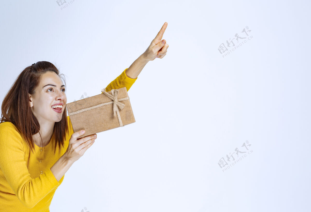 年轻穿黄衬衫的女孩拿着一个纸板礼盒 想找人送礼物服装奖项年轻人