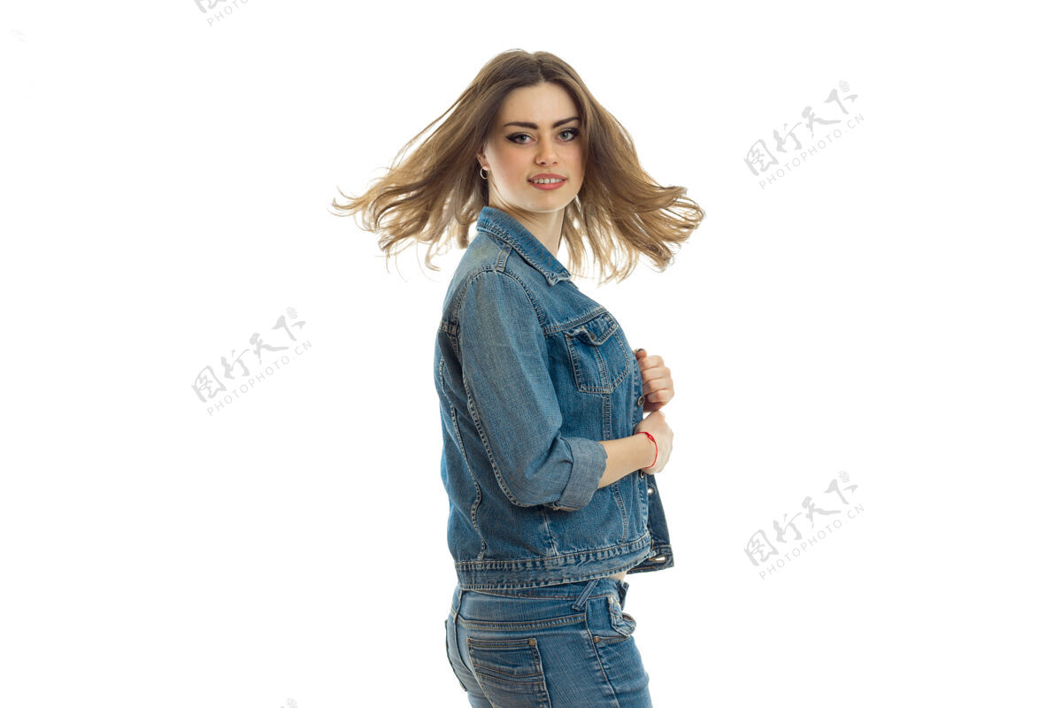 剪裁穿着牛仔裤套装的漂亮年轻女子站在一旁 微笑着孤立地站在白墙上成人人魅力
