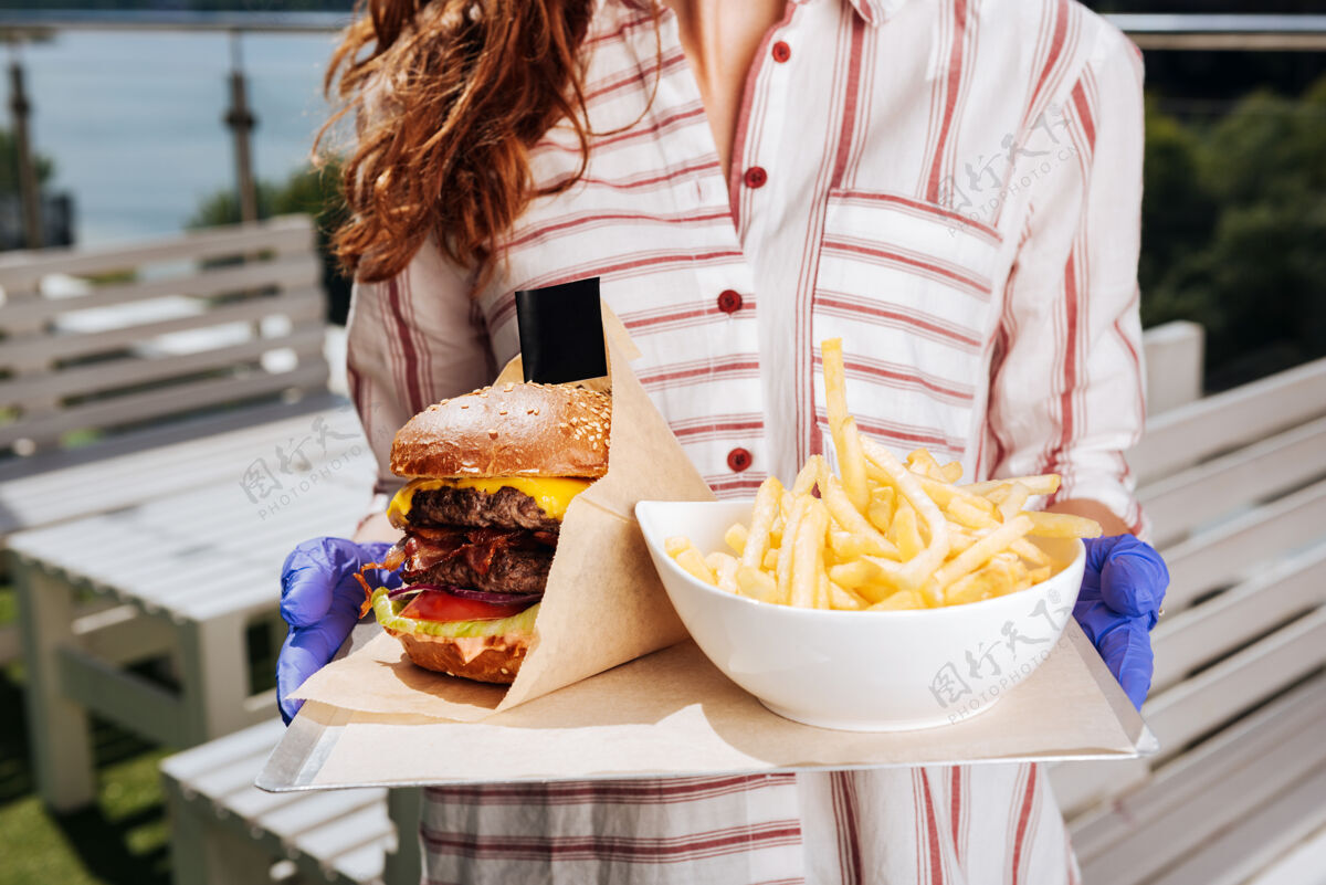 汉堡汉堡配薯条黑发女人穿着时髦漂亮的白衬衫拿着汉堡配薯条部分服务味道
