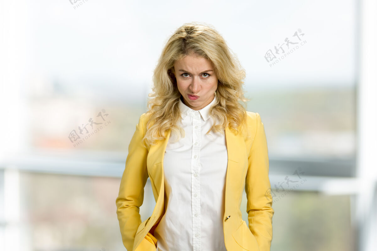表情严肃愤怒的金发女郎的肖像年轻恼怒的女人站着人类的面部表情正式的耳朵商业问题