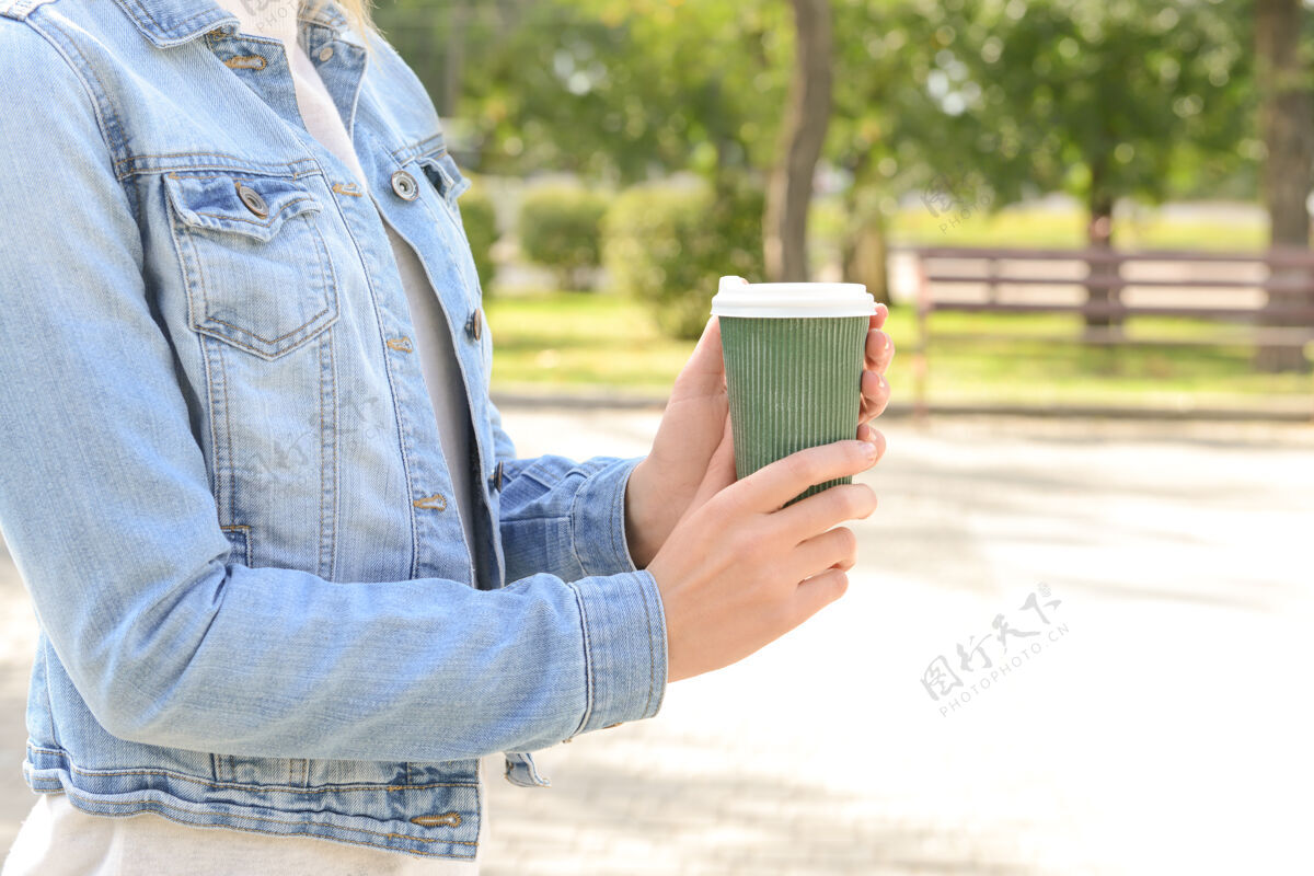 杯子在公园里拿着纸咖啡杯的女人盖子外卖自然