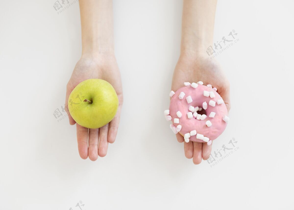 工作室双手紧握着甜甜圈和苹果食物生活方式保健