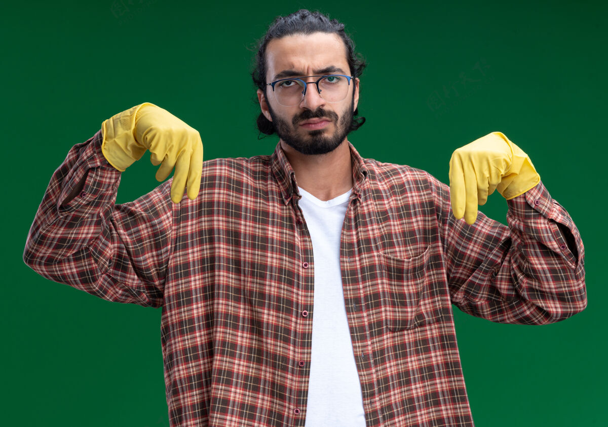 假装年轻帅气的清洁工穿着t恤 戴着手套 假装拿着隔离在绿色墙上的东西男人人年轻人