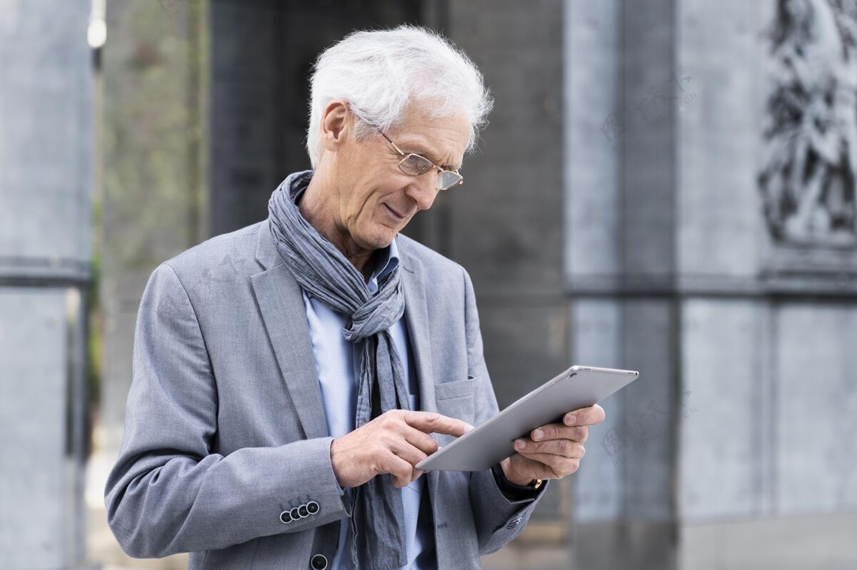 城市时尚的老男人在城市里使用平板电脑老年人老老年人