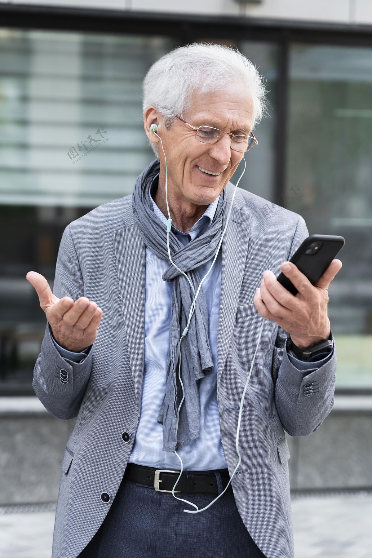 移动时尚的老男人在城市使用智能手机和耳机的视频通话设备老年人城市