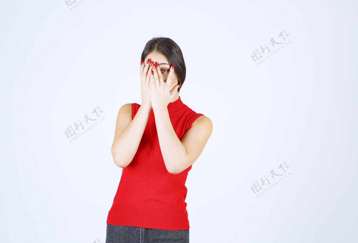 雇员穿红衬衫的女孩透过手指看年轻人年轻人眼睛