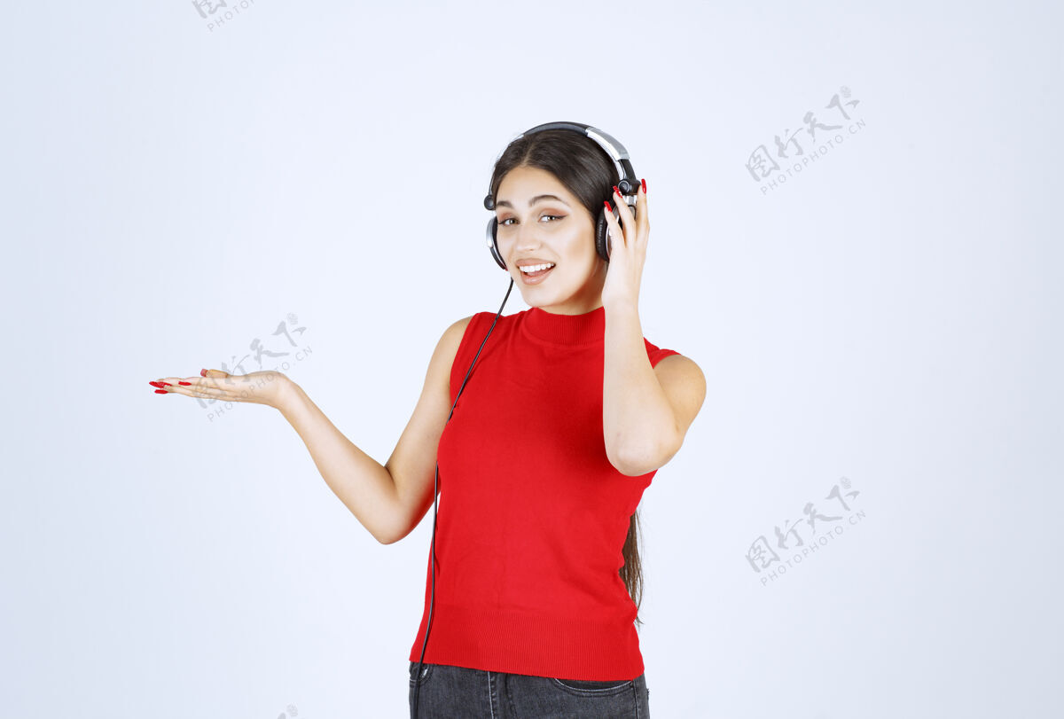 姿势穿着红衬衫的Dj女孩 戴着耳机 手上拿着什么东西或是什么东西人类模特年轻人