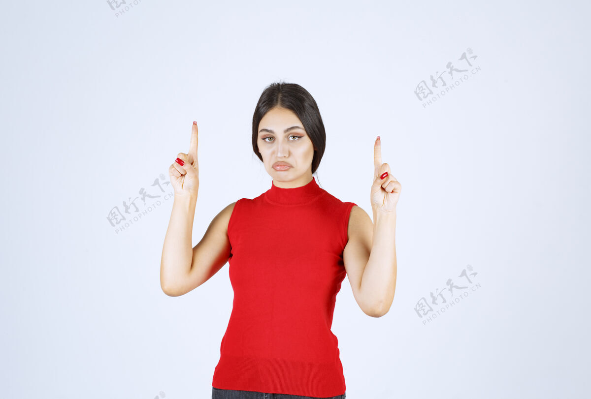 休闲穿红衬衫的女孩举手指着上面介绍模特女